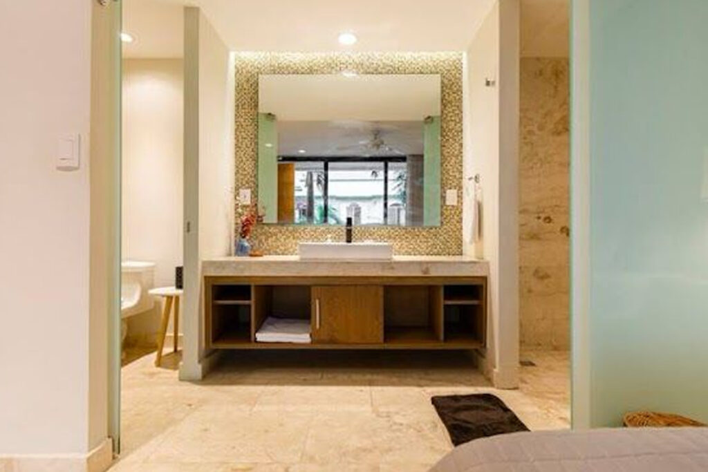 Lavamanos y espejo iluminado en el bano en suite de la habitacion principal del departamento